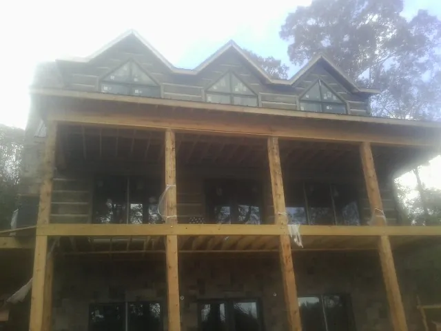 Dormers and porch framing on a large log home under construction — Roof Coating work by our crew in Cypress