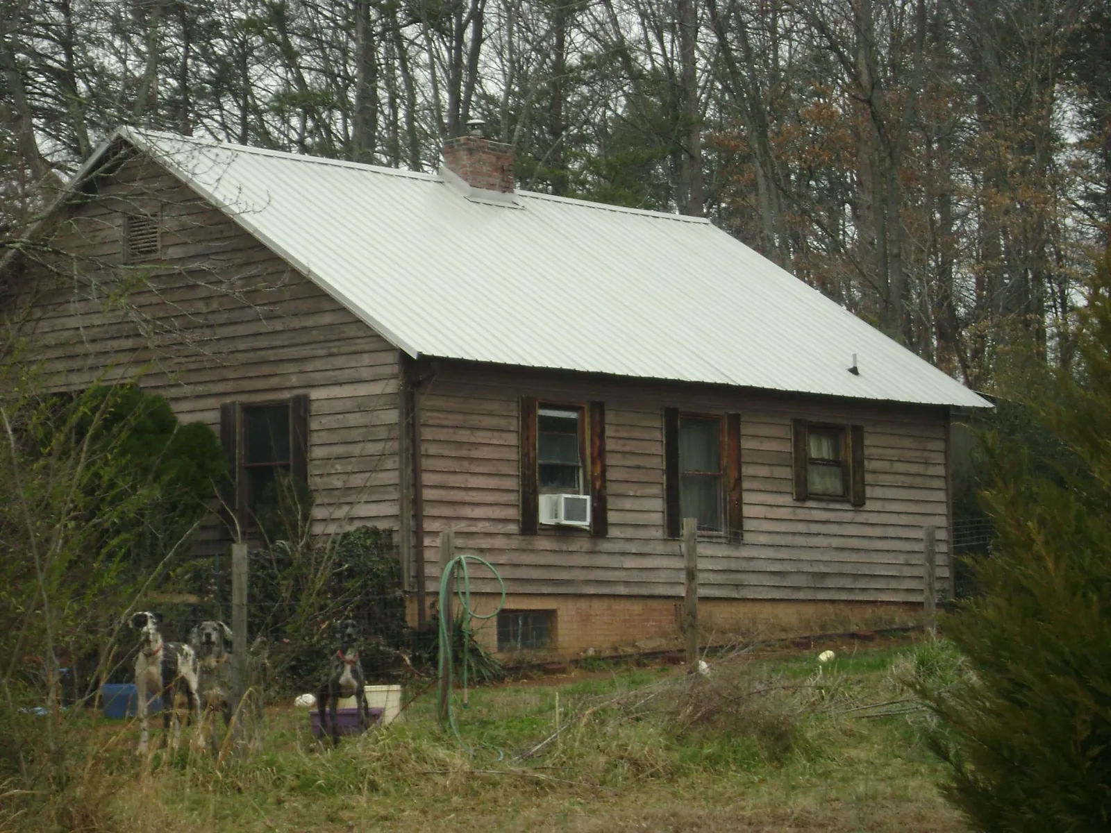 White metal roof on an old wood sided farmhouse, from a Metal Roof Installation job in Cypress